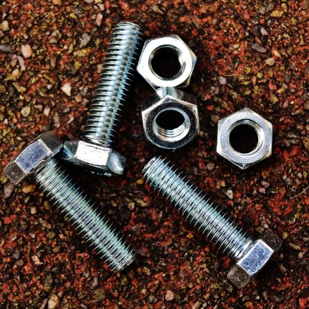 A set of three nuts and bolts against a brown background.