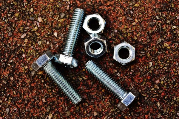 A set of three nuts and bolts against a brown background.