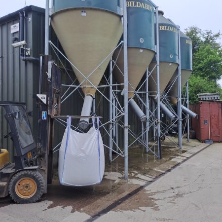 A forklift holding a tote bag up to be filled with bulk animal feed at RP George.