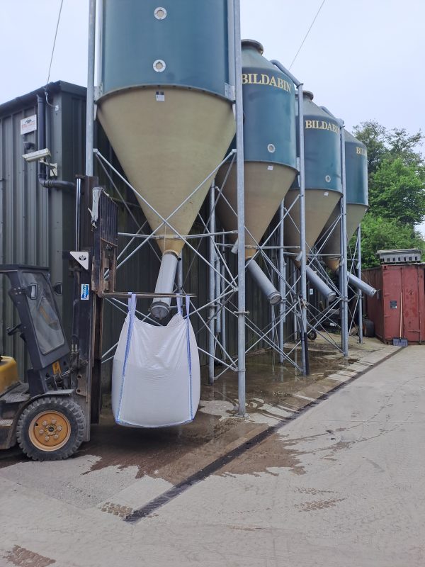 A forklift holding a tote bag up to be filled with bulk animal feed at RP George.