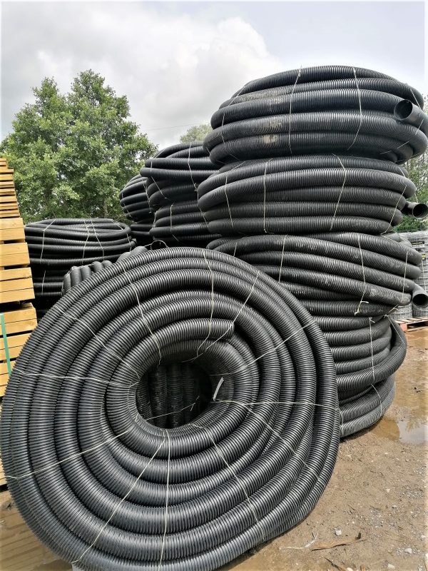 Several piles of black land drain coils stacked in the yard at RP George.